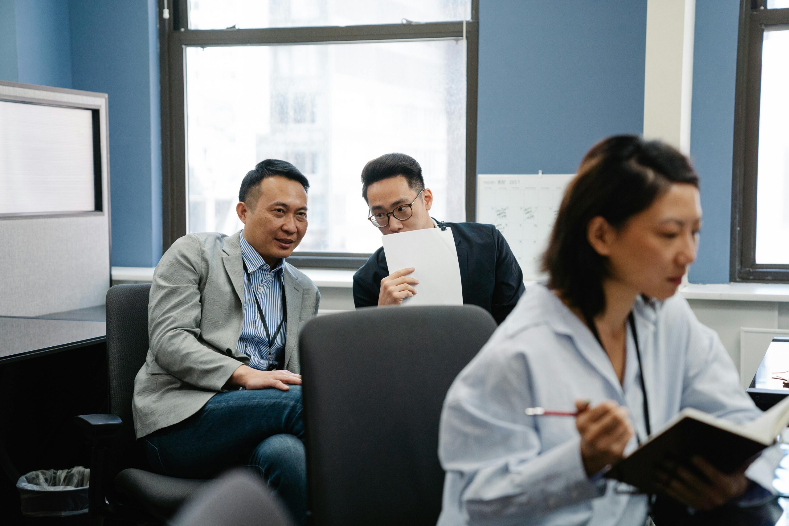Colleagues whispering during work in an office setting, signaling teamwork and collaboration.